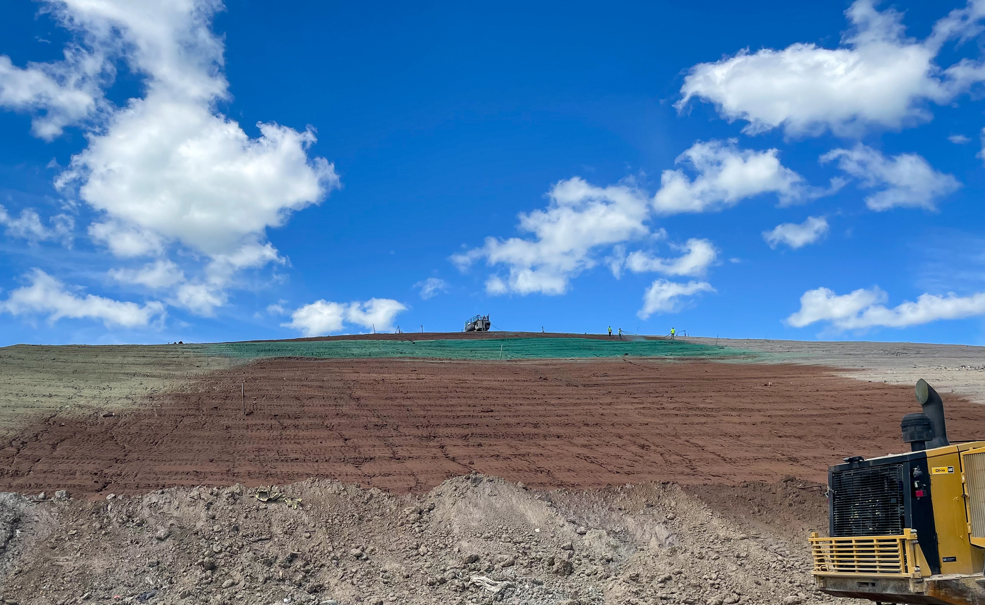 Hydroseeding a landfill hill.